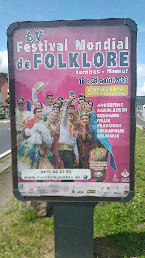 Photo prise au bord de la Meuse, début août 2023, d’une affiche pour le « Festival du folklore » à Namur et Jambes. Sur l’affiche, des personnes, toutes habillées de différents costumes traditionnels, se regroupent pour prendre un selfie.